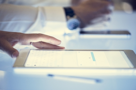 Hand on a digital tablet with downloading on a screen