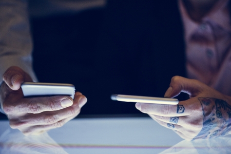 Hands with tattoo holding smartphone
