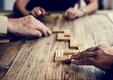 Group of people playing domino game on wooden table