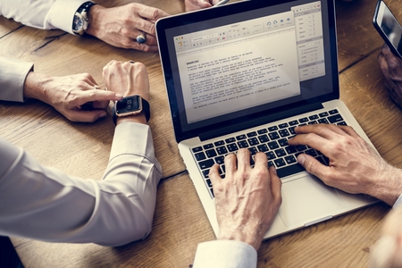 Hand setting a smartwatch and laptop