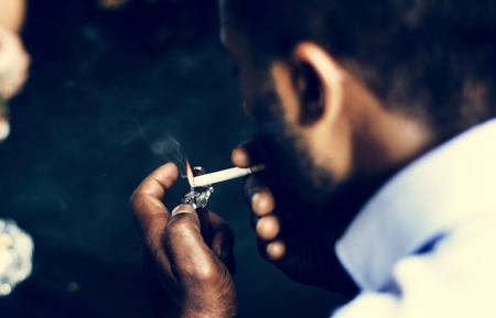 Rear view of man lighting up the cigarette in his mouth