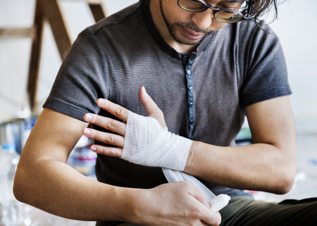 Man wrapping injured hand with bandage