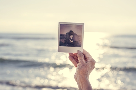 Old lady holding a photograph at the beach