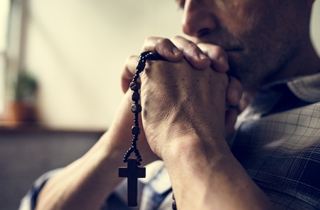Cloesup of hands holding cross praying