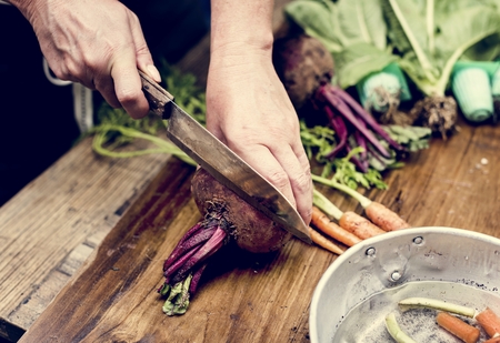 Closeup of hand with knife cutting fresh vegetable