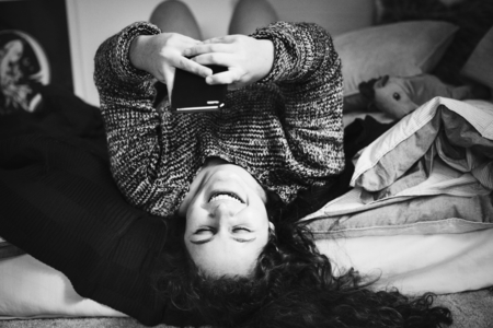 Teenage girl using a smartphone on a bed