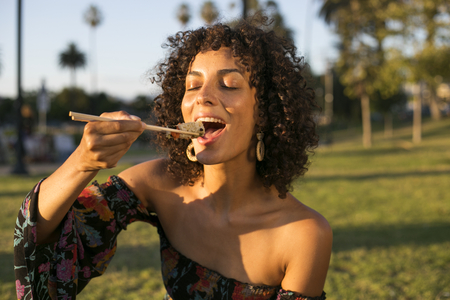 Woman eating sushi in the park