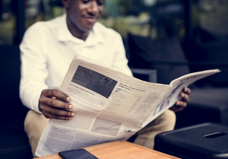 Photo for African descent man sitting reading a newspaper outdoor - Royalty Free Image