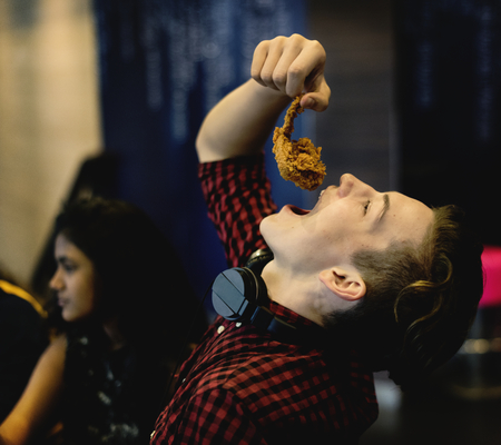 Close up of teenage boy eating fried chicken with his friends