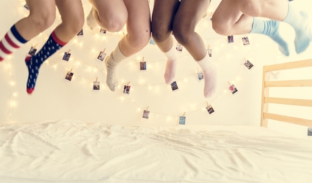 Closeup of two pairs of legs with socks jumping on the bed