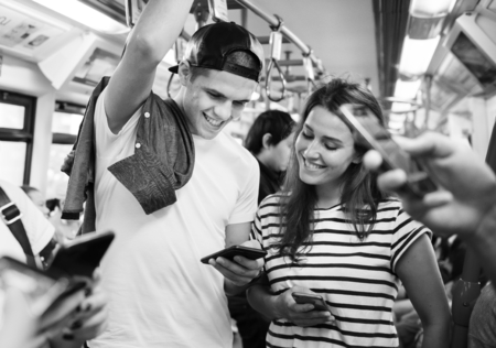 Group of young adult friends using smartphones in the subway
