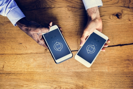 Hands holding a smartphone with sync symbol on screen