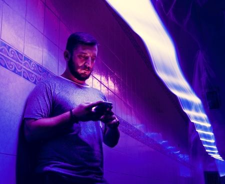 Closeup of a man using mobile phone in the dark with long exposure light