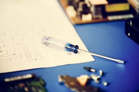 Closeup of screwdriver over circuit pattern guide line paper