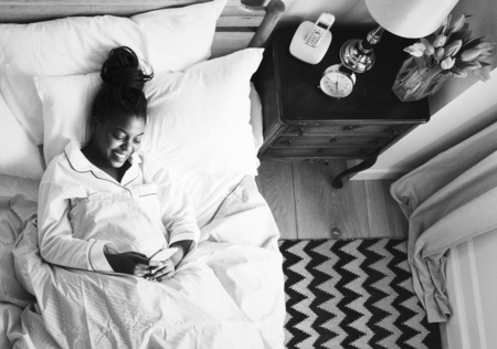 Smiling African American woman on bed using a cellphone