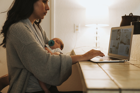 Mother using a computer and holding her baby