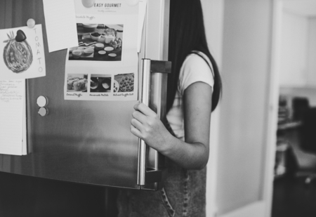 Girl picking something to eat out of the fridge
