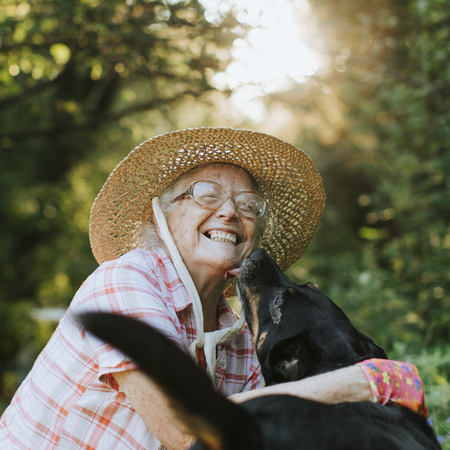 Happy senior woman getting kisses from her dog