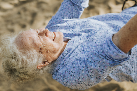 Cheerful senior woman on a swing at a playground