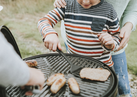 Mother assisting her child while grilling
