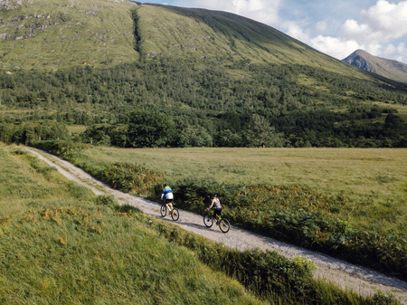 Couple cycling down a road in the Scottish Highlands