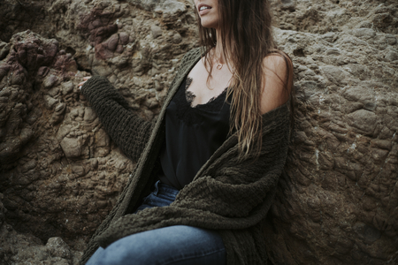 Mid section of woman leaning against a rock