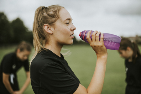 Female football player drinking from a water bottle
