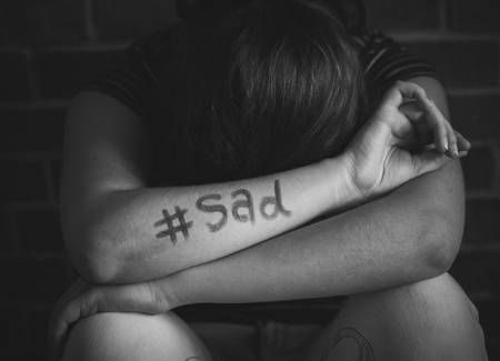 Girl with hashtag sad written on her arm