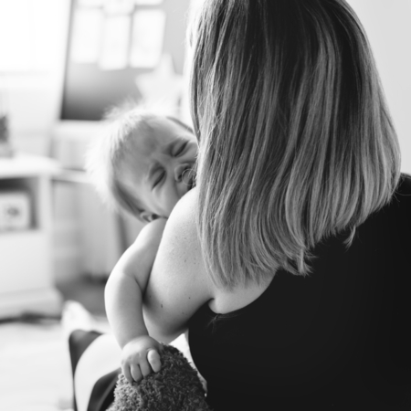 Back of a mom carrying a crying baby