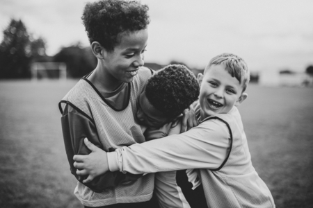 Photo pour Junior football team hugging each other - image libre de droit