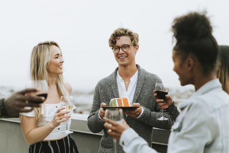 Foto de Cheerful friends celebrating at a rooftop birthday party - Imagen libre de derechos