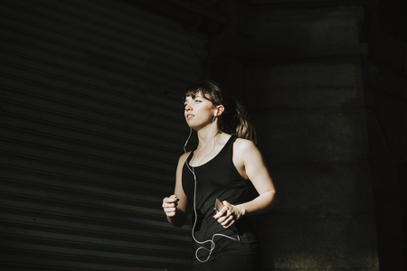 Sporty woman jogging in a dark alley