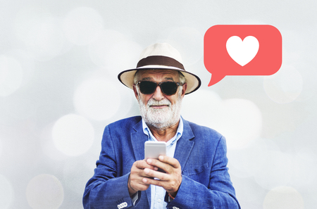 Stylish elderly man texting on his smartphone