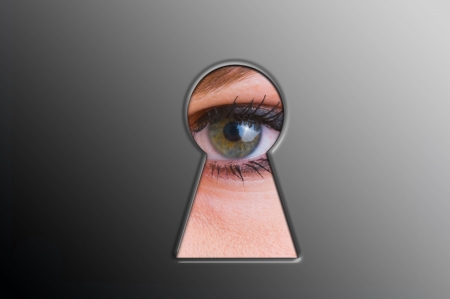 Woman looks through a keyholeの写真素材