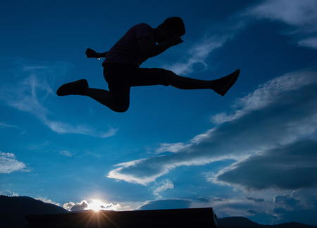 Silhouette of a jumping man on the skyの写真素材