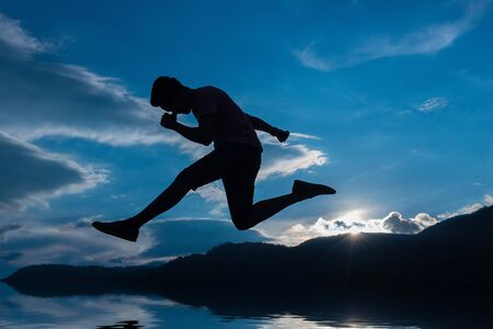 Silhouette of a jumping man on the skyの写真素材