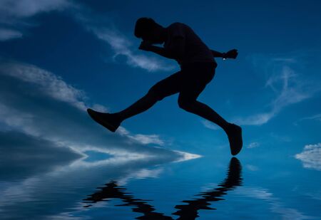 Silhouette of a jumping man on the skyの写真素材