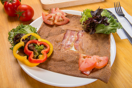 Ham and Egg Crepe,Galette complete. Traditional French buckwheat crepe with egg, cheese and ham at served at typical Breton pancake restaurant Creperie. On the wooden floor.の写真素材