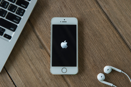 CHIANGMAI, THAILAND - June 22, 2015: New Apple Iphone5s in old wooden floor color on working table. The iPhone is the top-selling phone of any kind in some countries.のeditorial素材