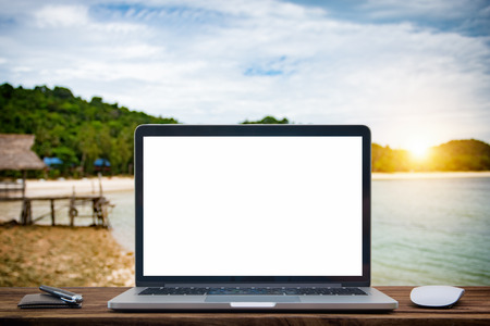Laptop with blank screen on table of Blur summer white sand beachの写真素材