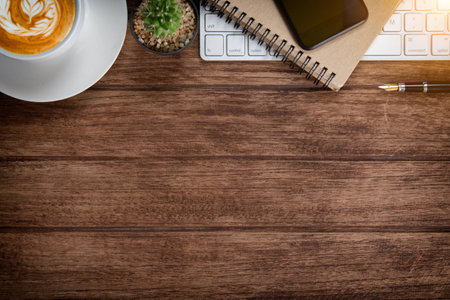 Office table with notebook, computer keyboard, mouse, cup of coffee, tablet pc and smartphone, Top view with copy space on wooden floorの写真素材
