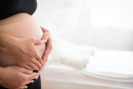 Cropped image of beautiful pregnant woman and her handsome husband hugging the tummyの写真素材
