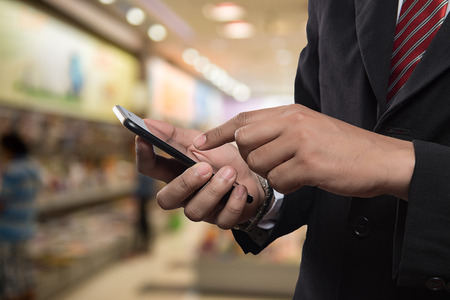 Business man in shopping mall using mobile phone.の写真素材