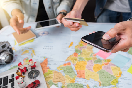 Young woman planning vacation using world map and compass along with other travel accessories. Tourist wearing brown hat looking at the world map.の写真素材