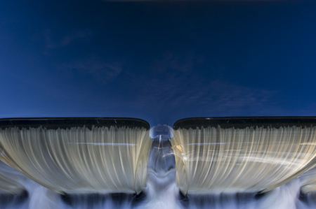 Water flows over a dam as the blue sky reflects off the water's surface.の写真素材