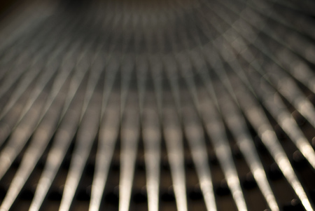 A metal park bench takes on a very different look when photographed out of focus and created a pattern of converging lines of light and dark.の写真素材