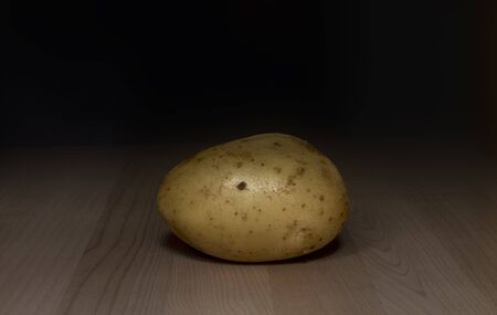 one yellow potato on wooden background , close upの写真素材