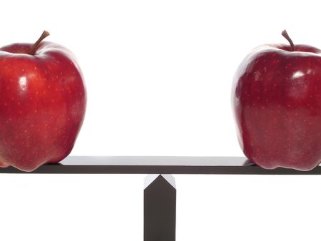 Comparing Apples to Apples on a balance beam isolated on white close-up.