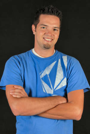 Young Man with Arms crossed, confident, smiling on a black background.