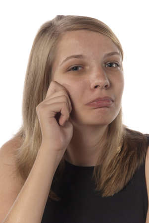 Young girl with hand near face as if crying and frowning while looking at the camera.の写真素材